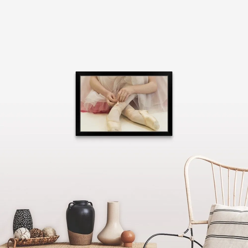 "A ballerina sitting on the floor tying her ballet shoes" Black Framed Print