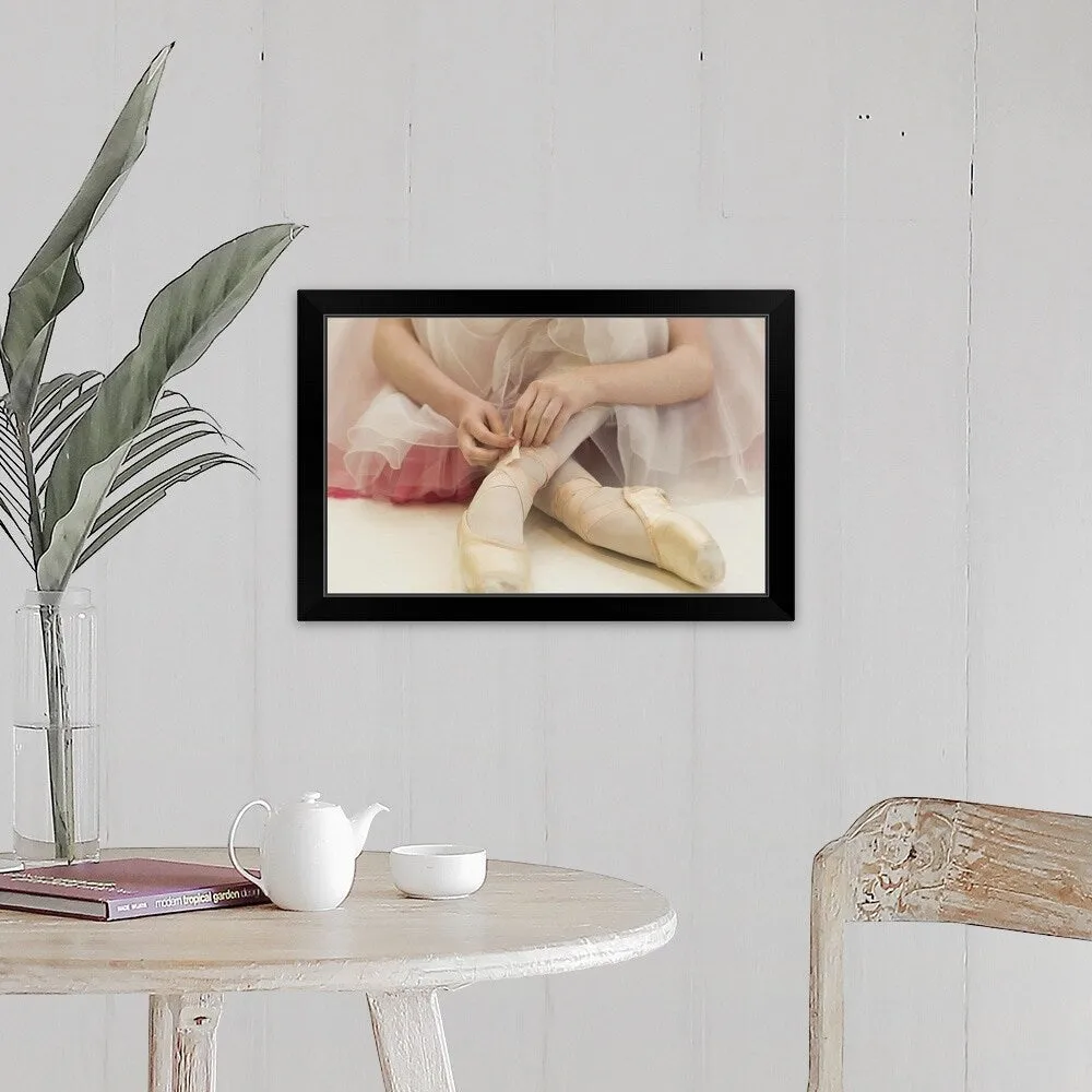 "A ballerina sitting on the floor tying her ballet shoes" Black Framed Print